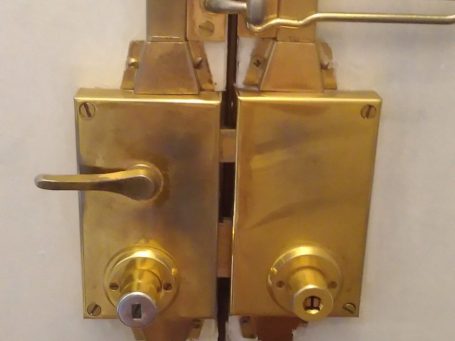 Deux serrures dorées sur une porte avec poignées et clés.