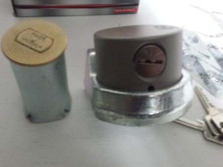 Cadenas de sécurité avec clé et cylindre métallique, sur fond gris.